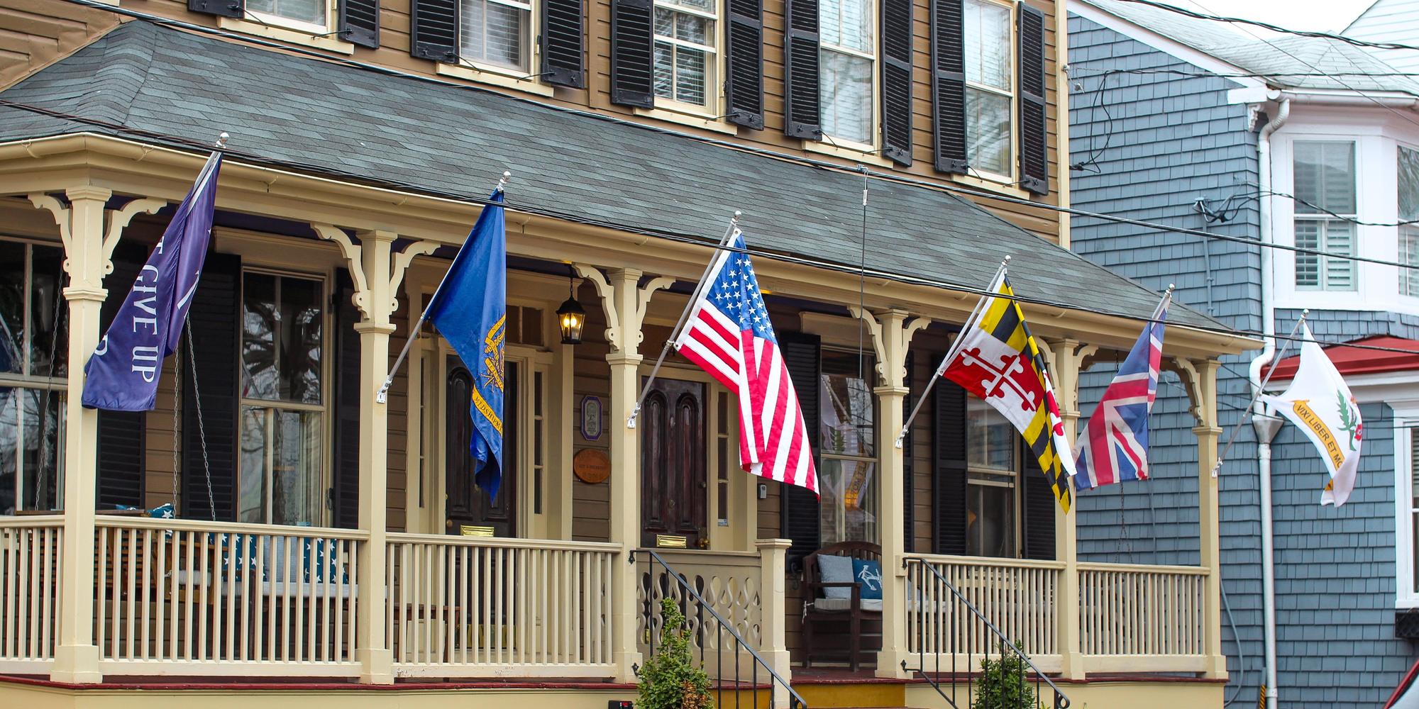 Six flags flying from angled brackets along one house porch