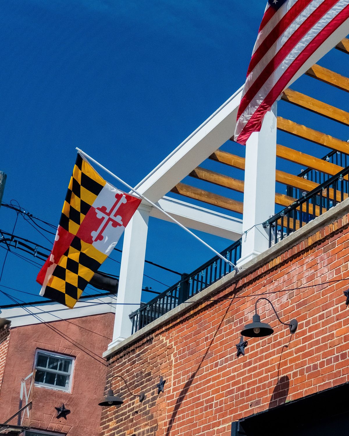 The Maryland state flag flying beside the national flag on house brackets