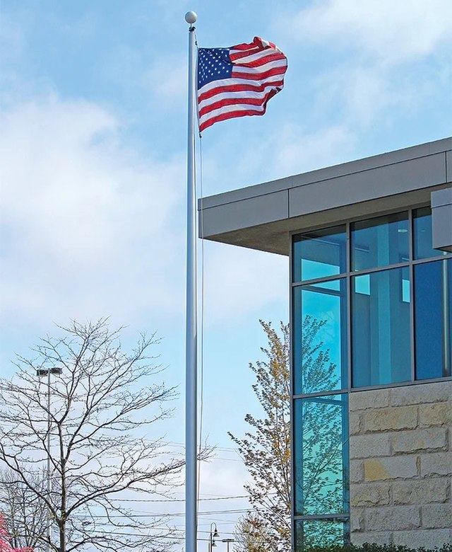 A commercial flagpole flying the American flag beside an office building