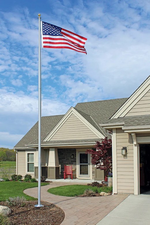 A residential flagpole flying the American flag in the front garden of a house