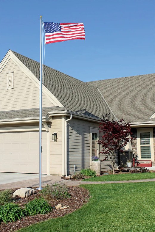 An American flag flying from a flagpole set in the front garden of a house